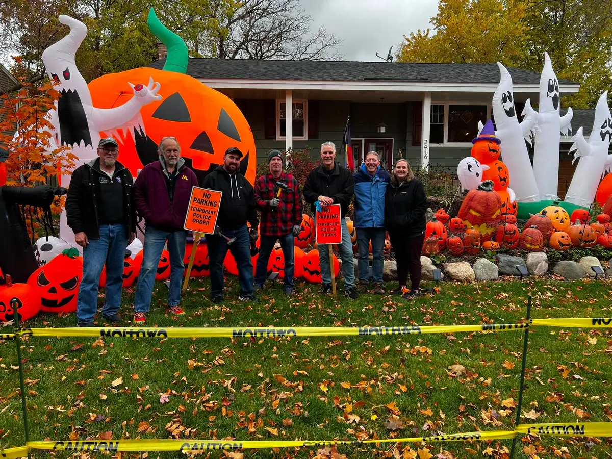 Neighbors posing together in front of a decorated home